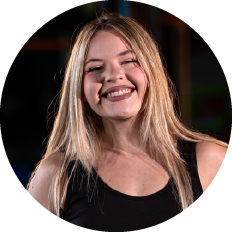Portrait of a smiling woman with long blonde hair wearing a black sleeveless top, circular crop.